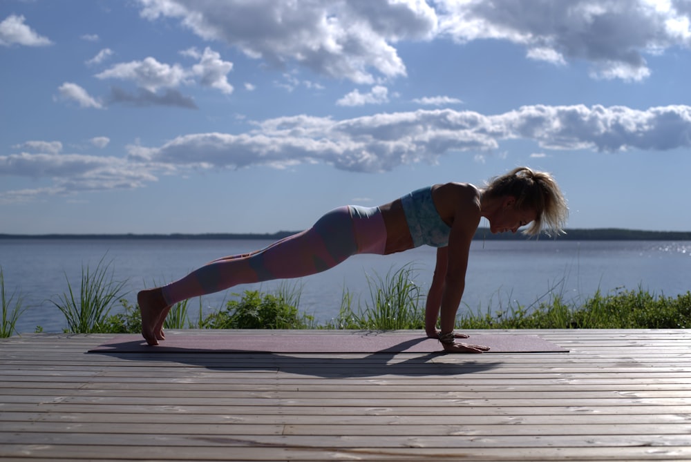 woman in blue sports bra and blue denim shorts standing on wooden dock during daytime