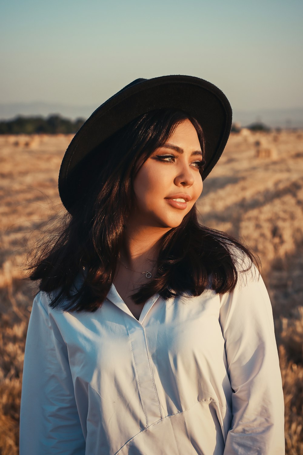 woman in white dress shirt wearing black fedora hat