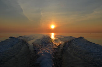 A serene ocean scene at sunrise with a sleek outboard motor gently cutting through calm waters.