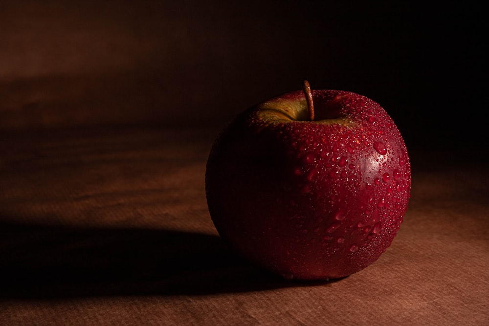 manzana roja sobre mesa de madera marrón