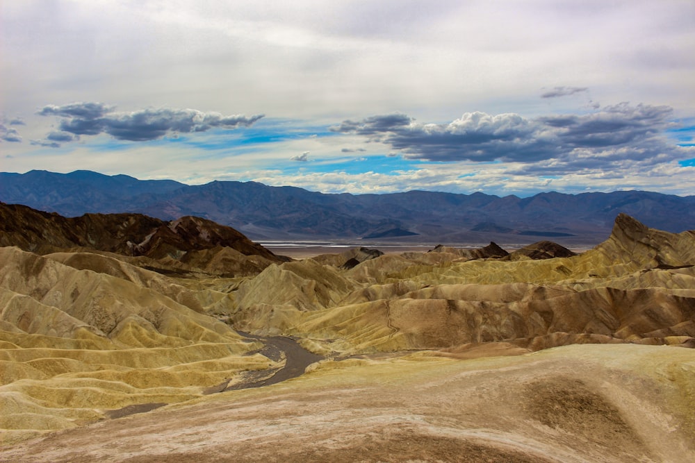 brown mountains under white clouds and blue sky during daytime