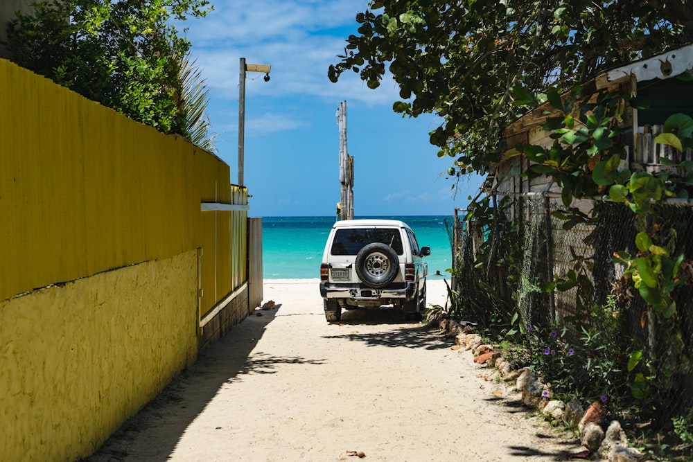 black car parked beside yellow building during daytime