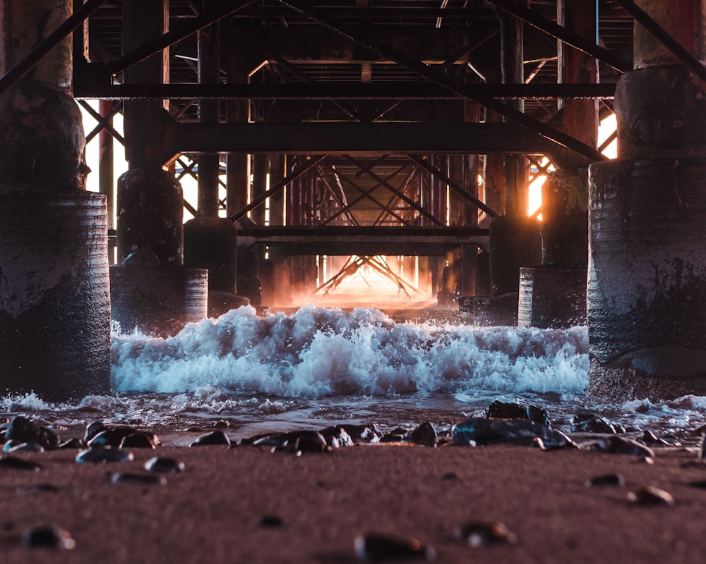 water falls under bridge during daytime