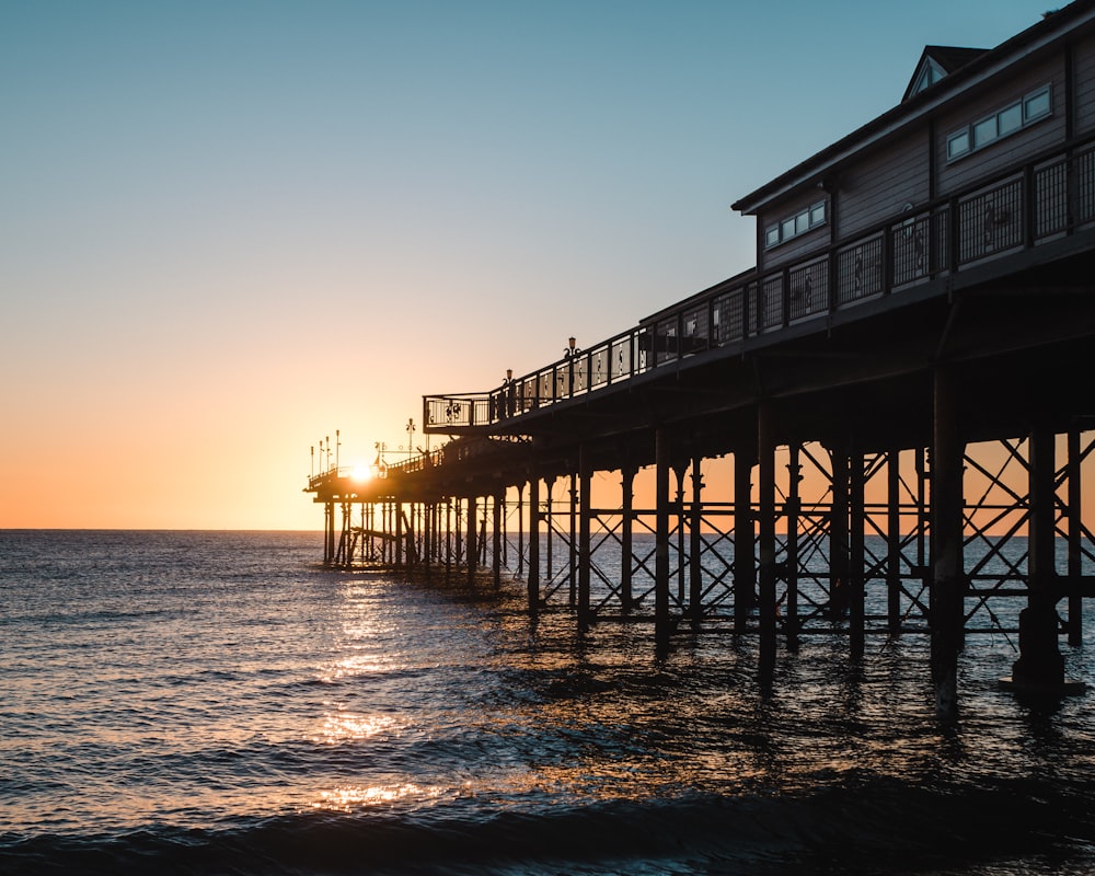 brown wooden house on sea during sunset