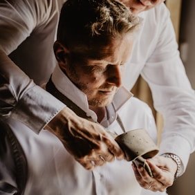 man in white dress shirt holding black ceramic mug