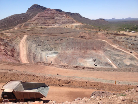 High-resolution image of coal mining logistics with heavy machinery and stockpiles under a clear blue sky.