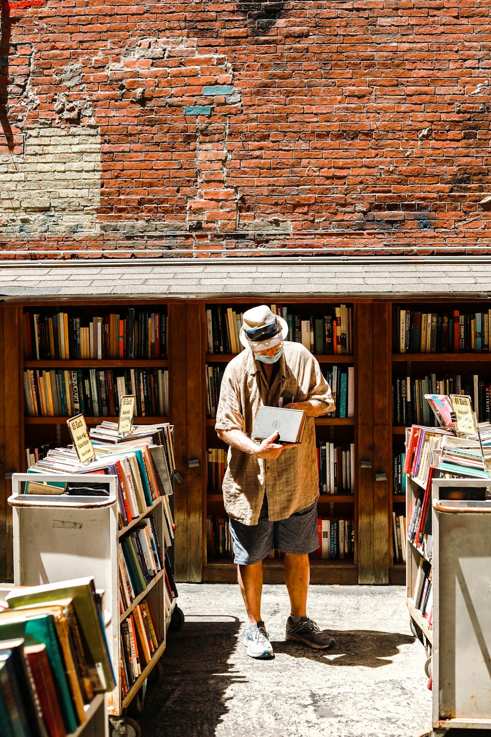 man in brown hat standing beside books