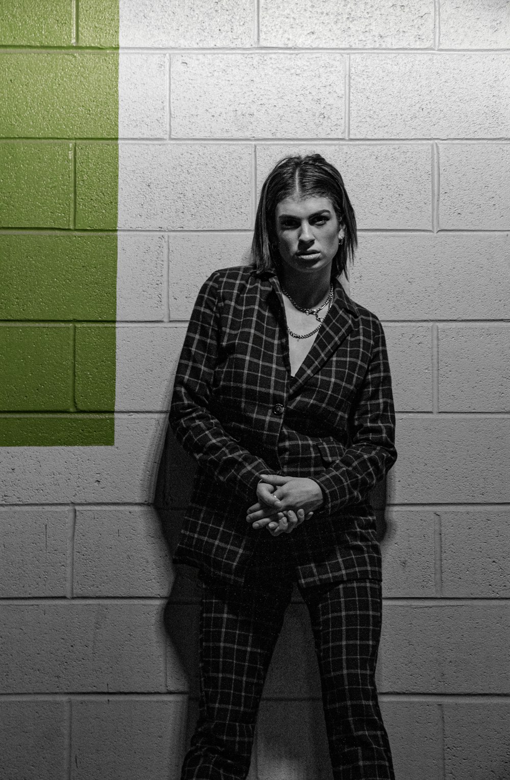 woman in black and white checkered dress shirt standing beside brick wall