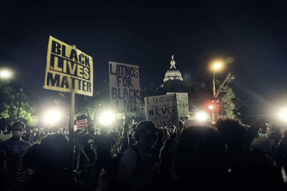 people standing near white and black street sign during night time