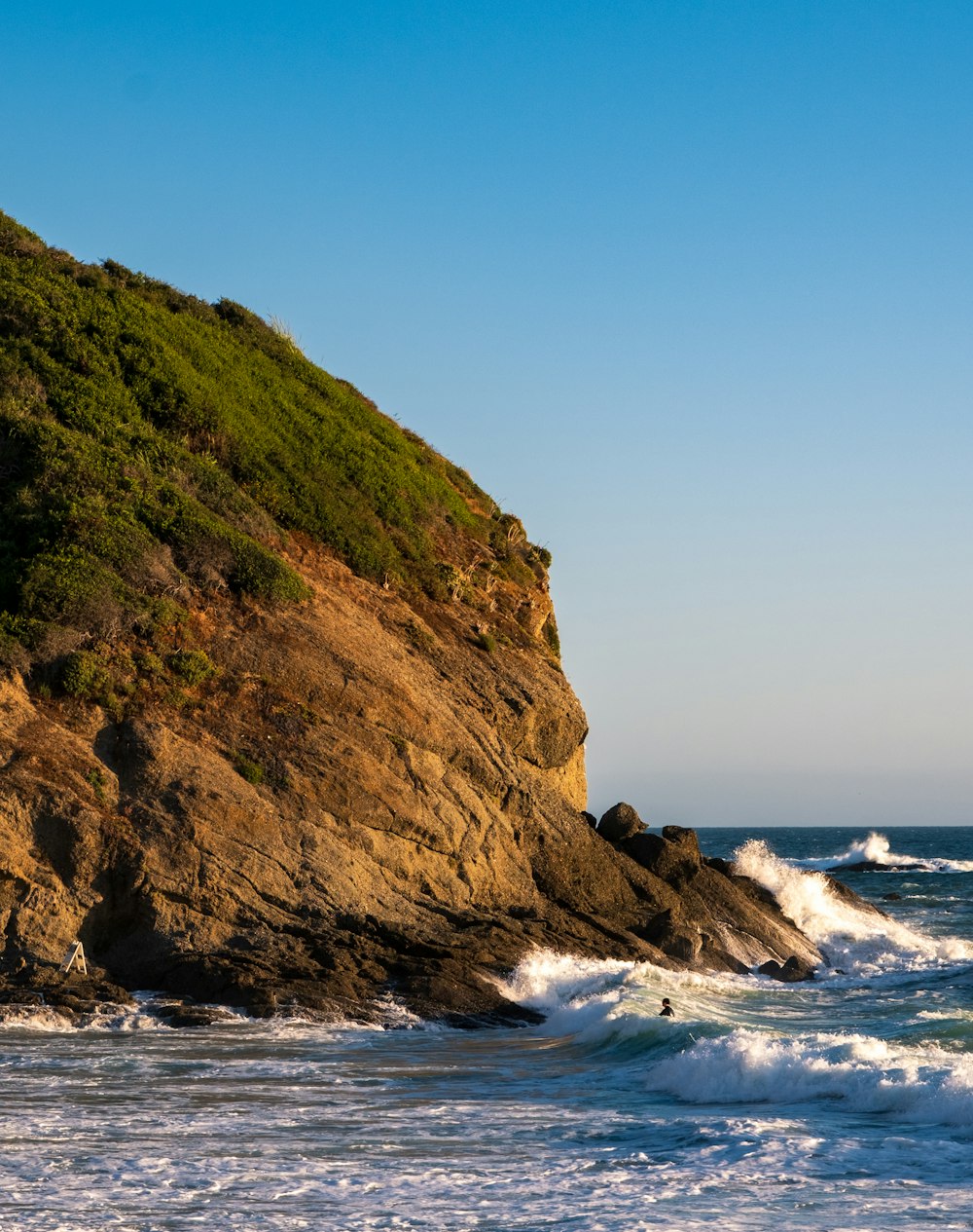 brown and green mountain beside sea during daytime