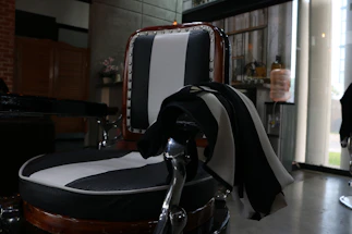 A sleek black and gold-themed contact desk with a vintage barber chair in the background.
