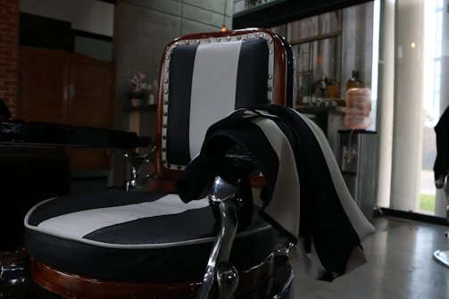 A sleek black and gold-themed contact desk with a vintage barber chair in the background.