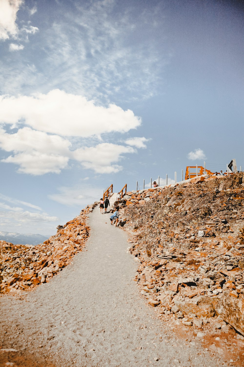people walking on rocky field under blue and white sunny cloudy sky during daytime