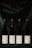 Four wine bottles are evenly lined up against a dark, velvety background. Each bottle features a label displaying the year 2019 with a white background and a yellow zigzag pattern.