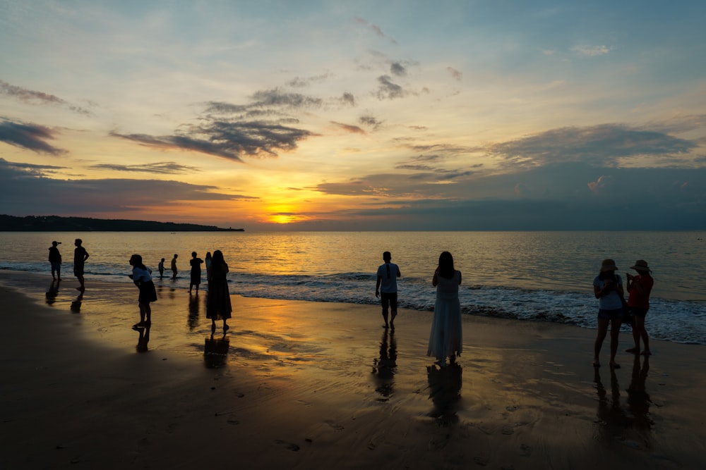 Menschen, die während des Sonnenuntergangs am Strand spazieren gehen