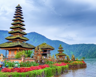 brown and green temple near lake and green mountain under blue sky during daytime