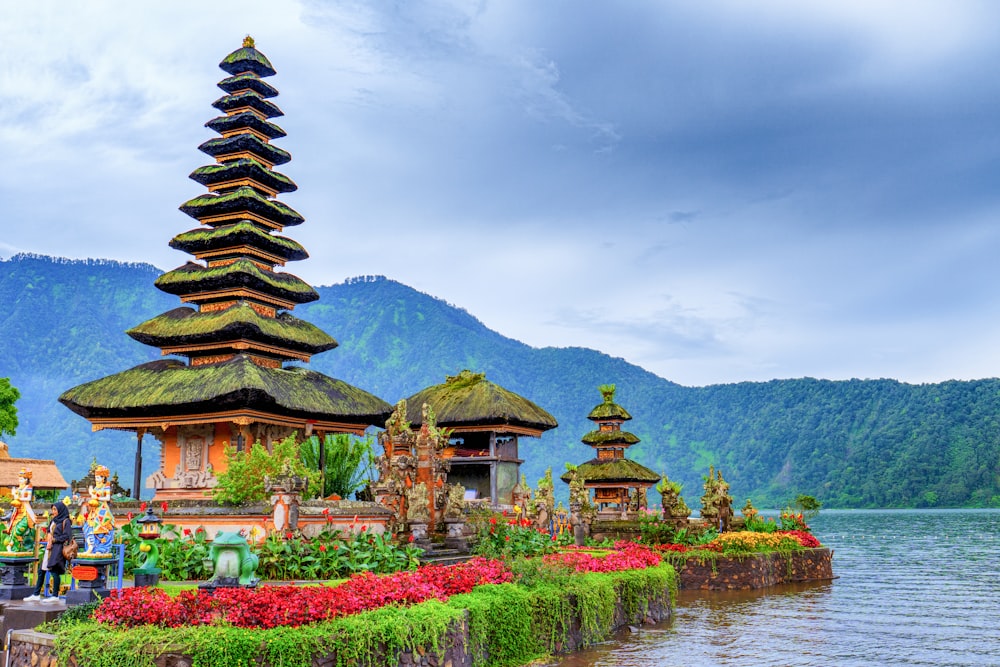 Templo marrón y verde cerca del lago y la montaña verde bajo el cielo azul durante el día