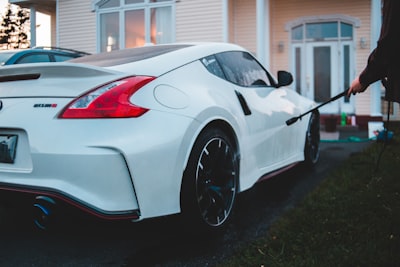 white porsche 911 parked near white house nissan zoom background