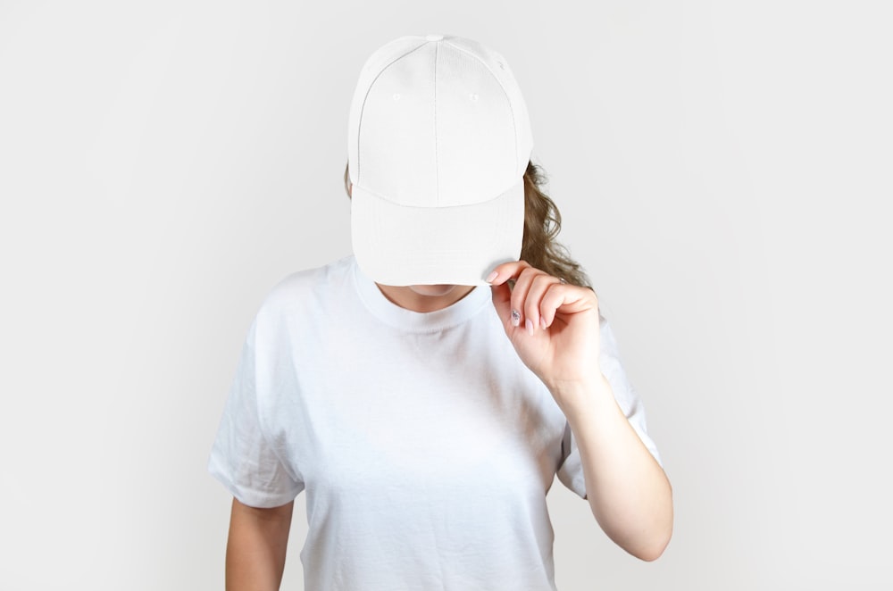 白いフェイスマスクで顔を覆う白いクルーネックTシャツの女性
