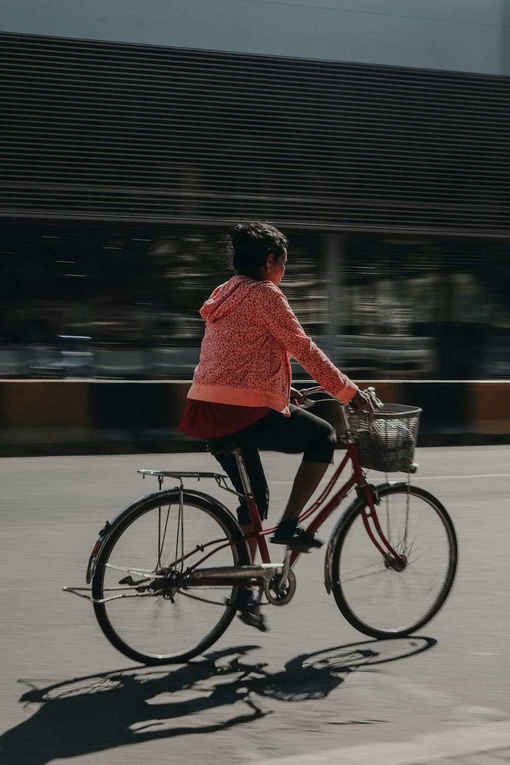 woman in red long sleeve shirt riding on black bicycle