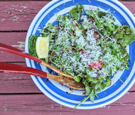 A vibrant plate of fresh salad with mixed greens, cherry tomatoes, and lemon wedges.