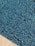A close-up view of a swimming pool with a shimmering water surface. The pool is lined with small blue tiles that create a textured, mosaic pattern. The edge of the pool features a beige stone border, adding contrast to the vibrant blue water.