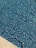 A close-up view of a swimming pool with a shimmering water surface. The pool is lined with small blue tiles that create a textured, mosaic pattern. The edge of the pool features a beige stone border, adding contrast to the vibrant blue water.