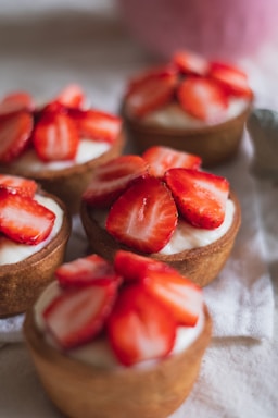 Close-up of an elegant strawberry tart with fresh cream and ripe strawberries on a rustic wooden table.