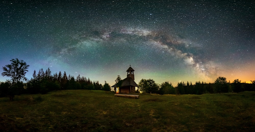 brown house on green grass field under blue sky with stars during night time