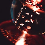 Reflective spheres and water droplets create a mesmerizing optical illusion with warm, glowing light and textured surfaces. The focus on shining liquid beads and a patterned background provides an abstract, artistic composition.