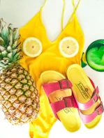 a pineapple, a pair of sandals and a pineapple on a yellow towel