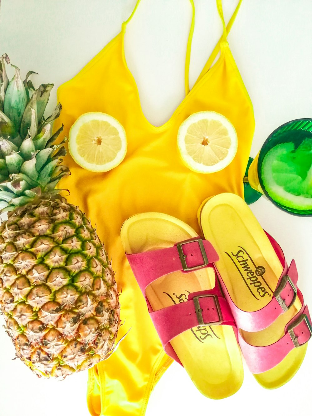 a pineapple, a pair of sandals and a pineapple on a yellow towel