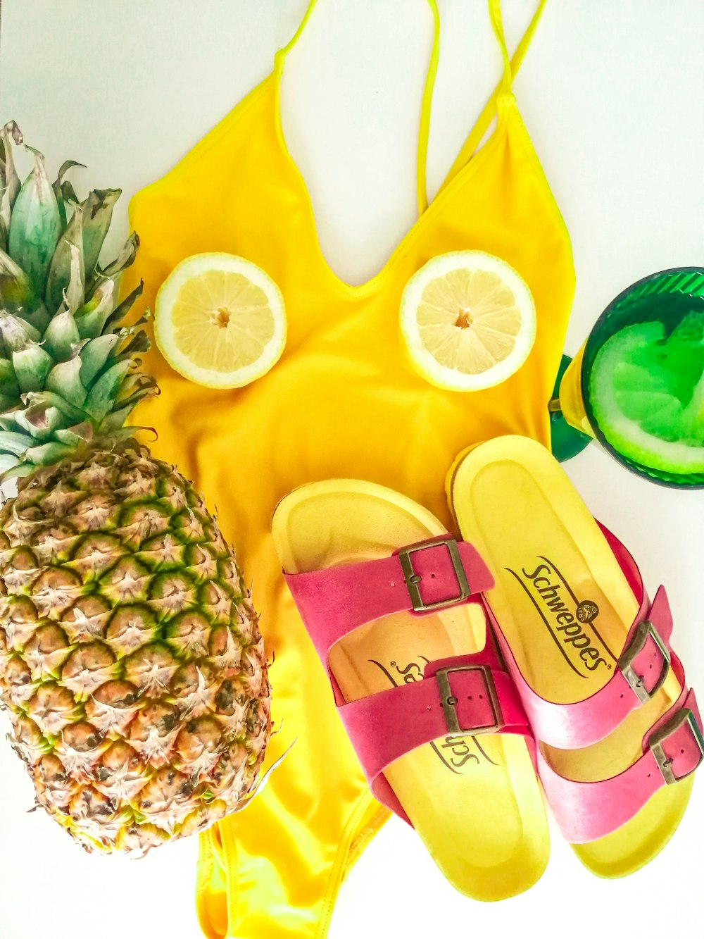 un ananas, un paio di sandali e un ananas su un asciugamano giallo