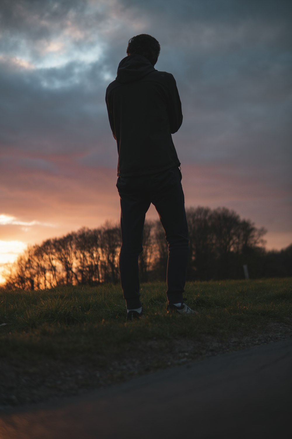 silhouette of person standing on green grass field during sunset