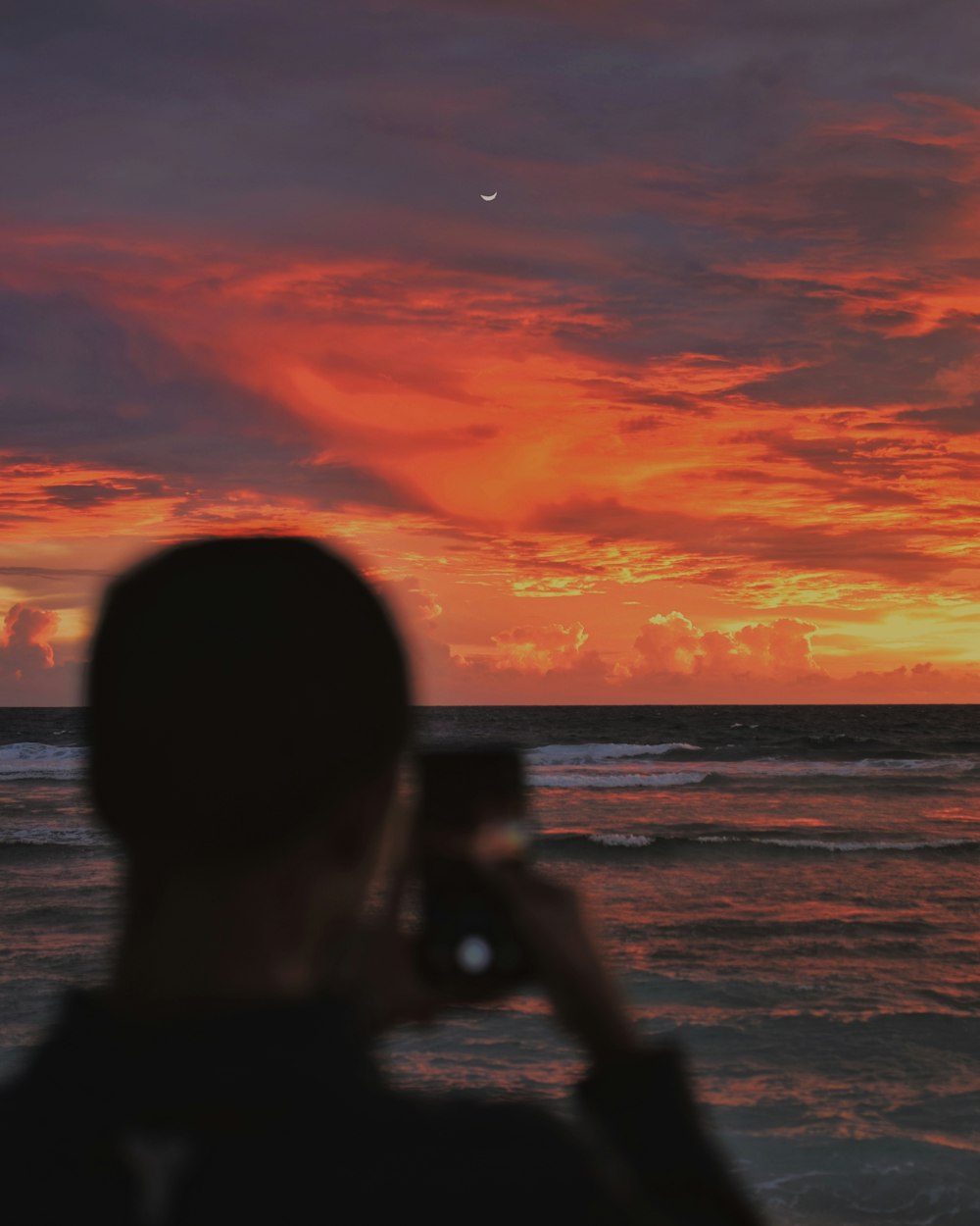 Silhouette eines Mannes, der den Sonnenuntergang fotografiert