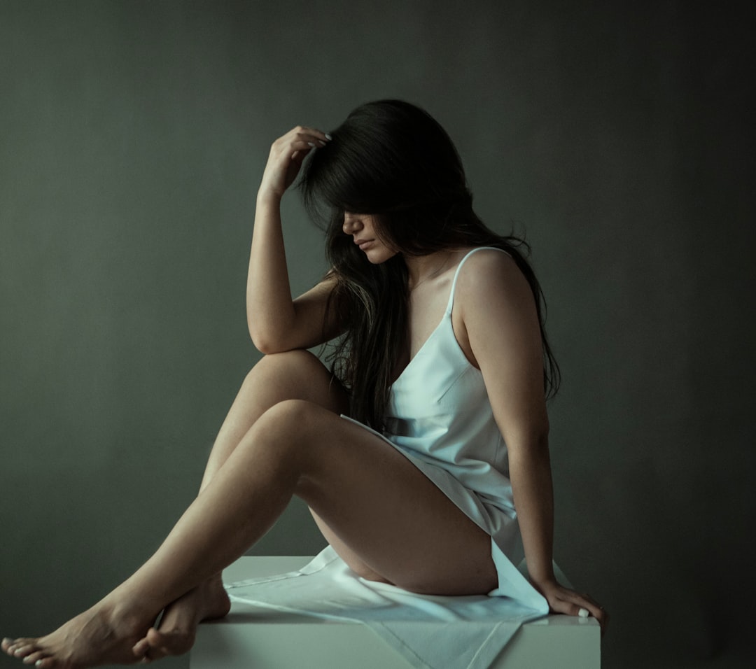 woman in blue tank top and white skirt sitting on white textile