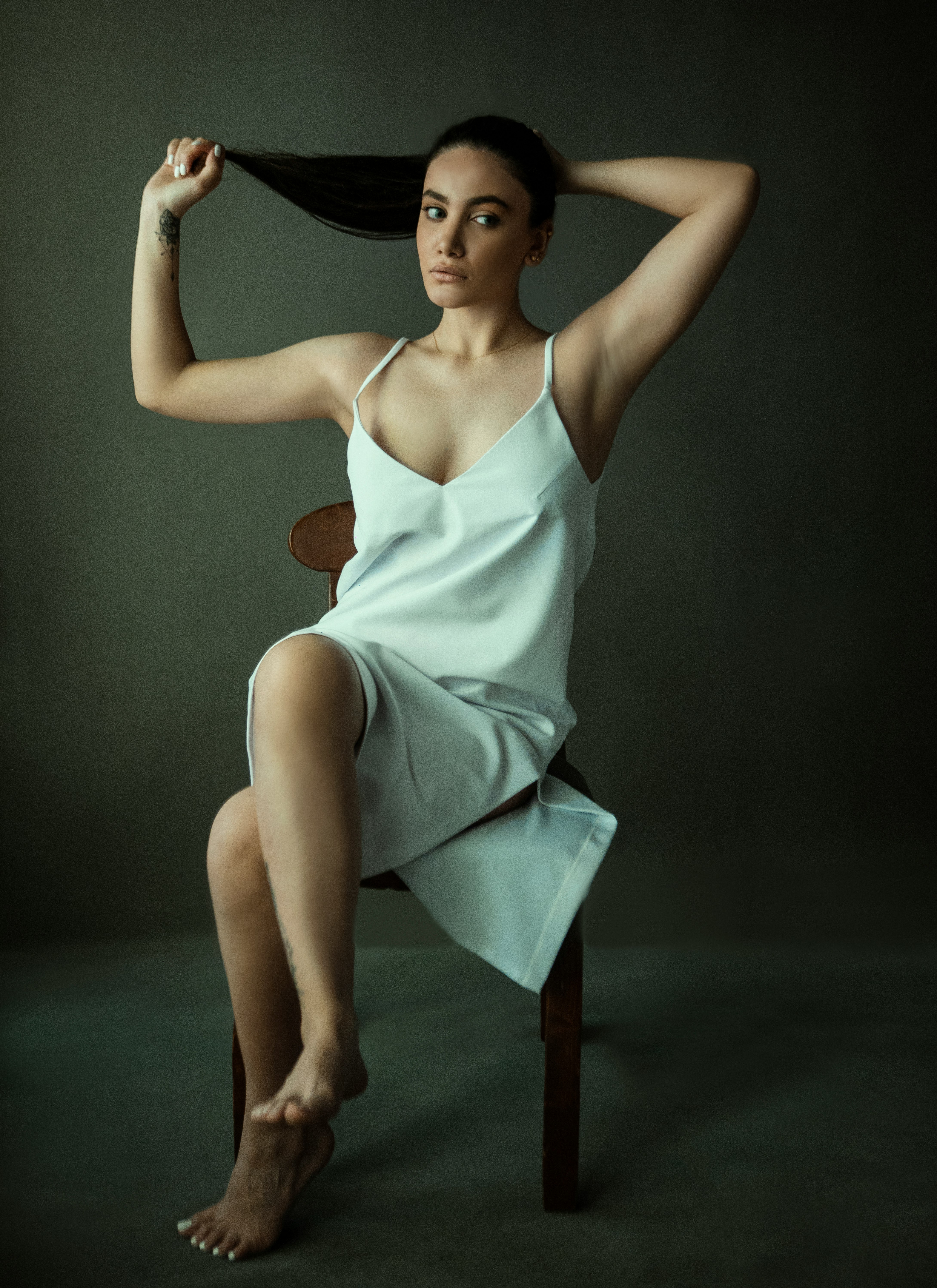 woman in teal spaghetti strap dress sitting on brown wooden chair