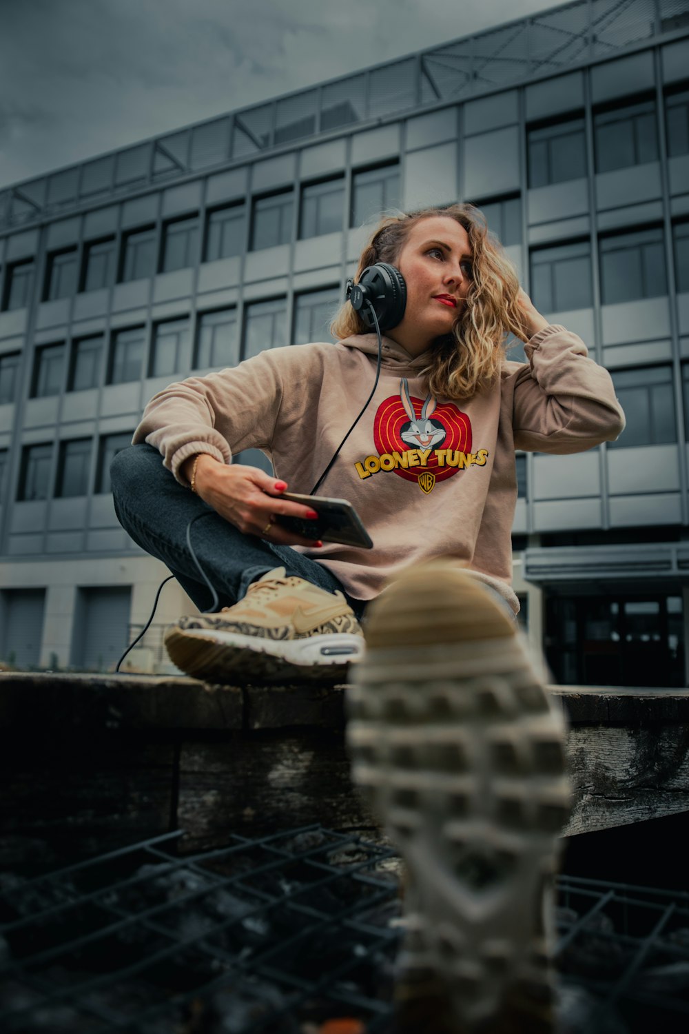 woman in brown hoodie and gray pants sitting on concrete bench during daytime