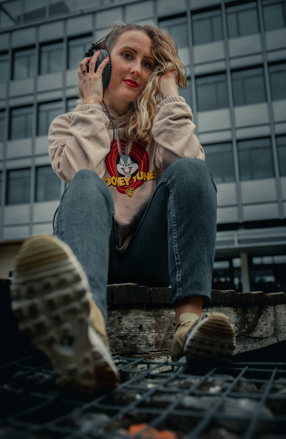 Femme en jean bleu et veste grise assise sur des escaliers en béton