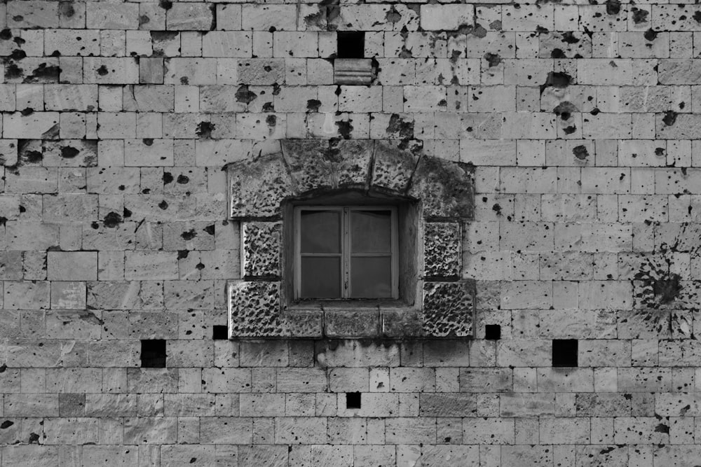grayscale photo of window on brick wall