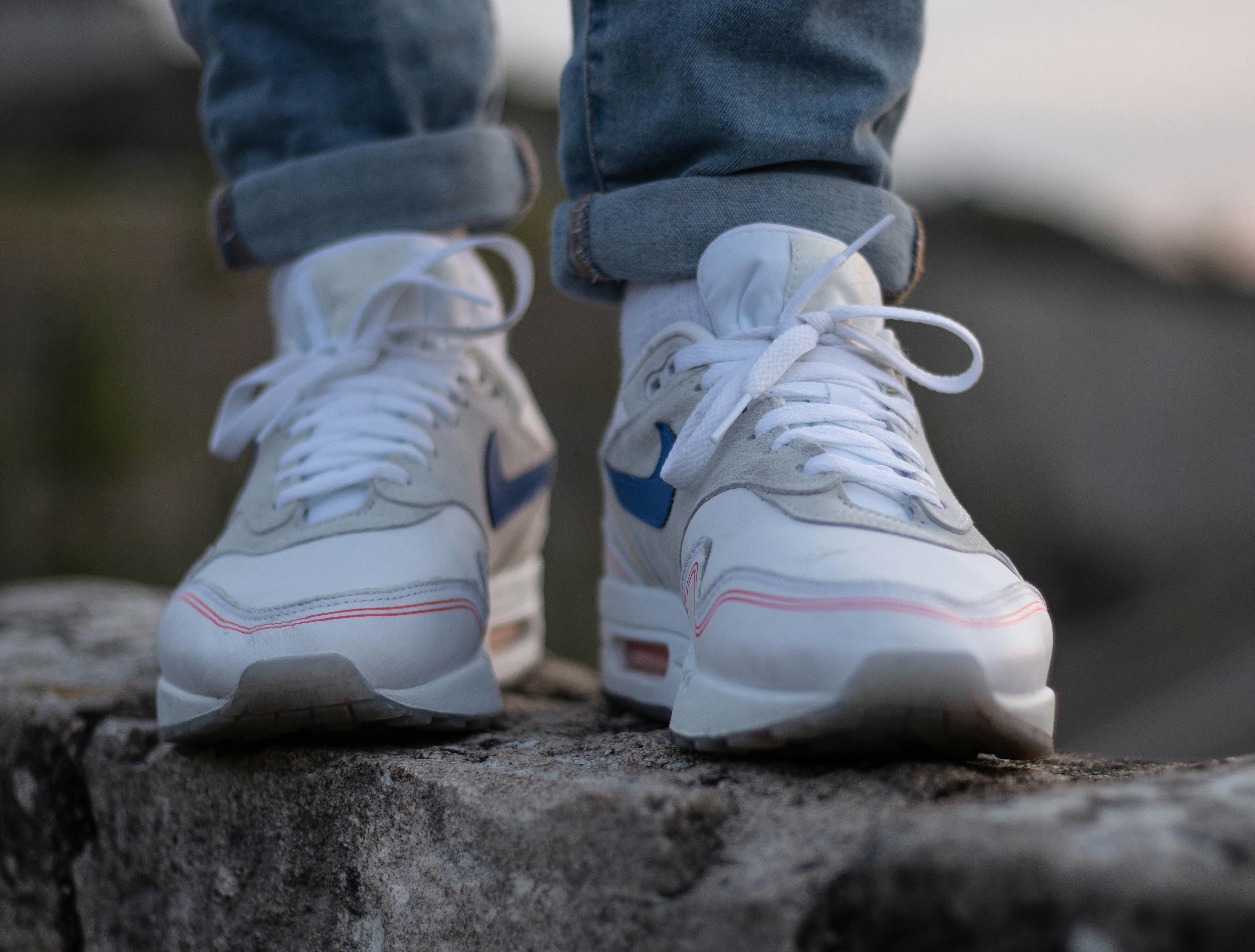 person in blue denim jeans wearing white and purple nike sneakers