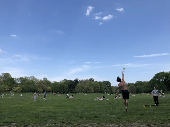A vibrant scene of people enjoying various sports activities outdoors, with a clear sky and energetic atmosphere.