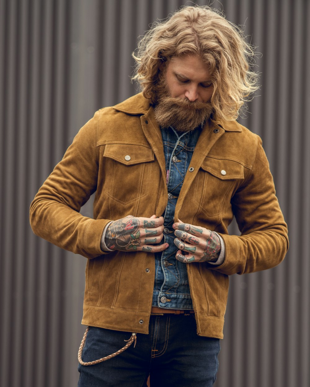 a man with long hair and a beard wearing a brown jacket