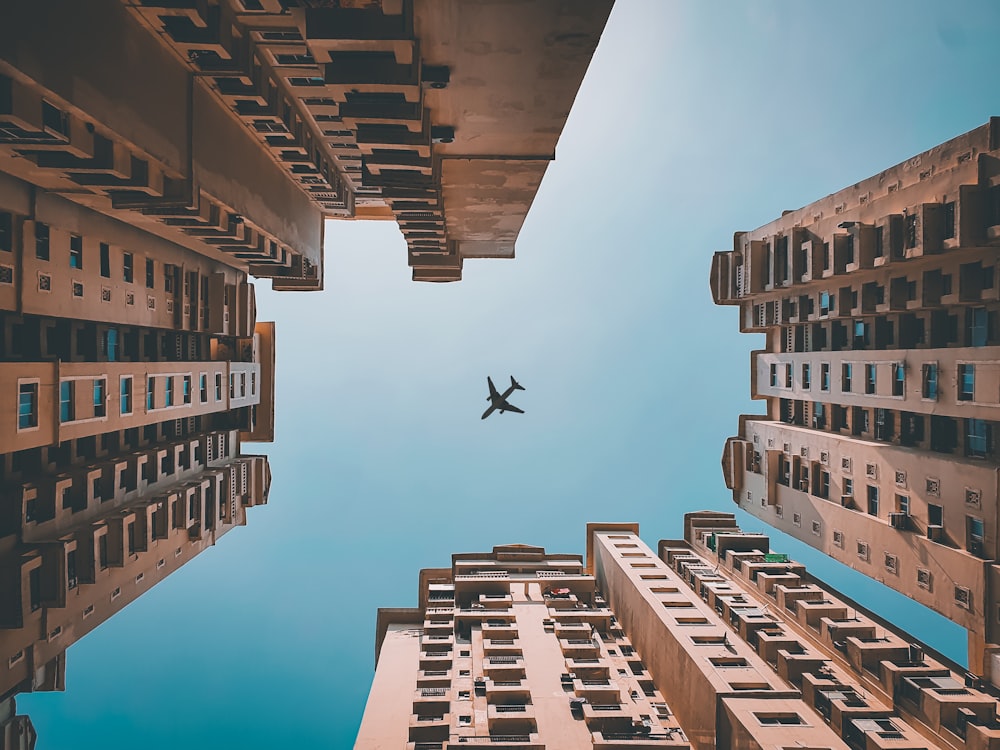 airplane flying over high rise buildings during daytime