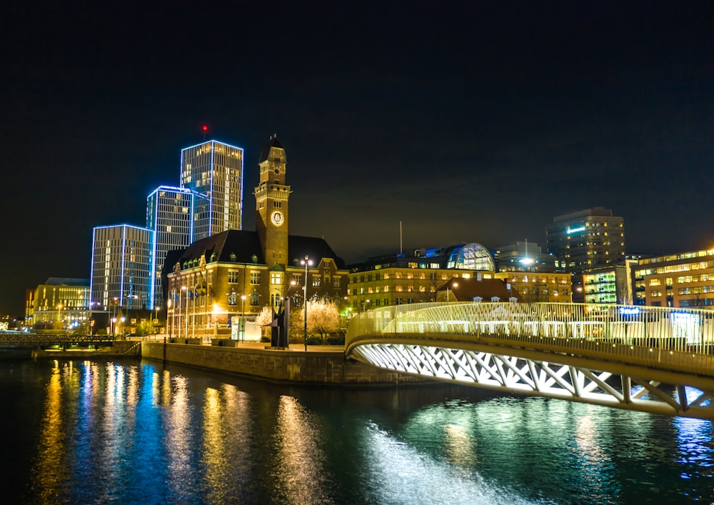 lighted bridge near city buildings during night time