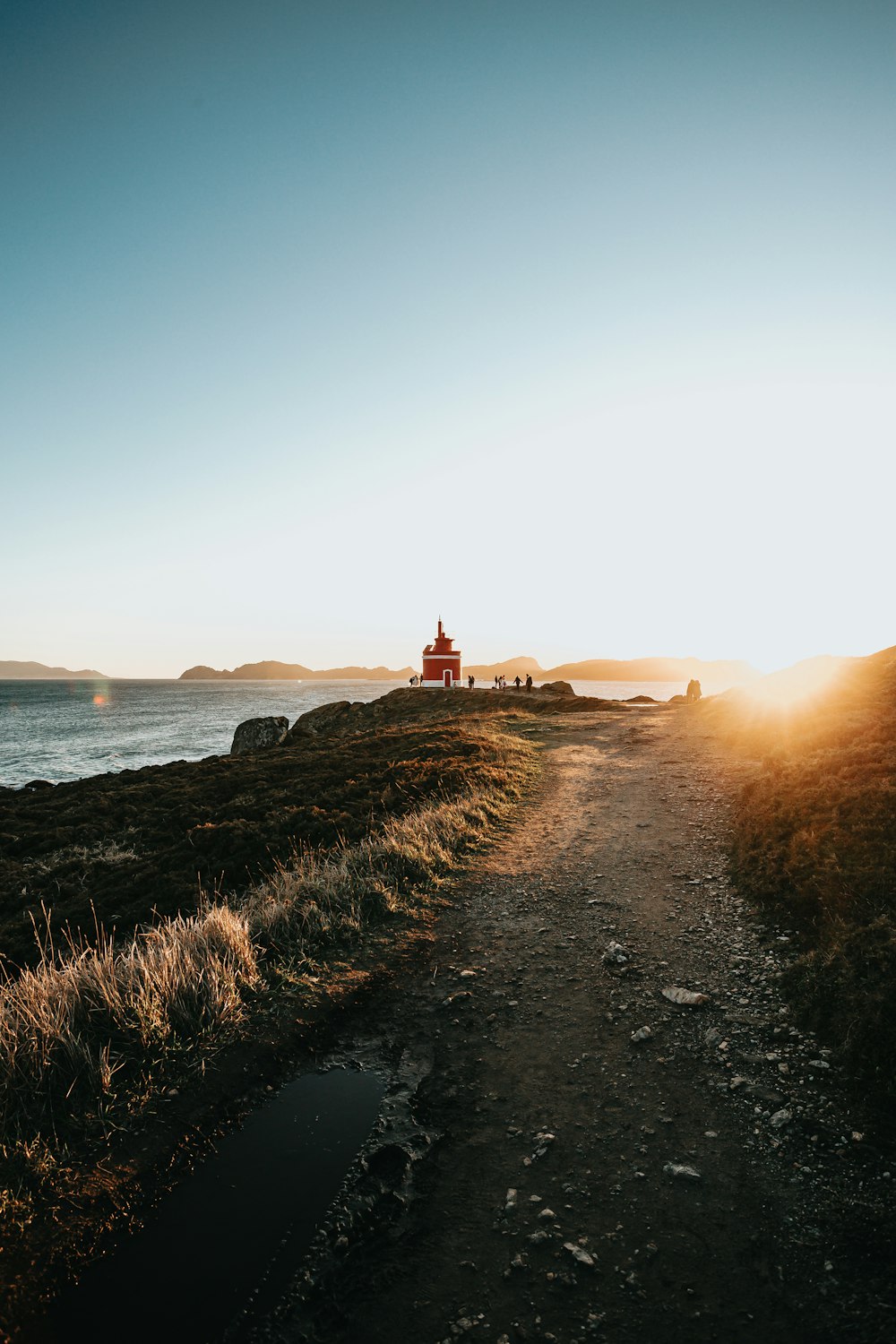 red and white lighthouse near body of water during sunset