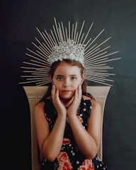 A soft pastel illustration of a little princess with a golden crown surrounded by sparkling stars and delicate flowers.