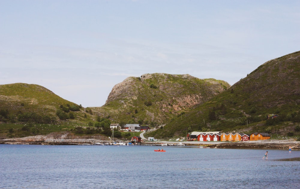 red and white boat on sea near green mountain under white sky during daytime