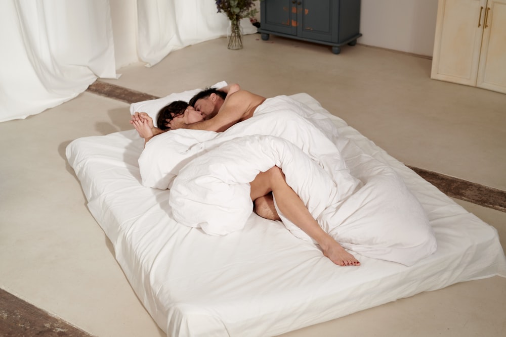 Frau liegt auf dem Bett mit weißer Decke bedeckt