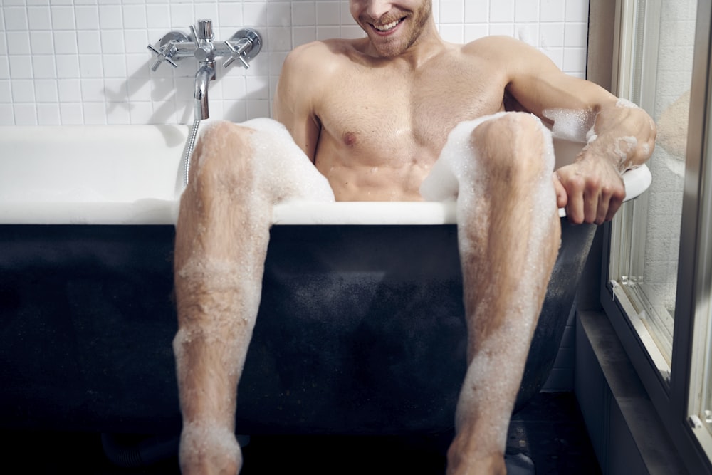 topless man sitting on bathtub